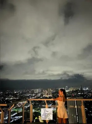 a woman standing on top of a building overlooking a city at Staycation by Darvy in Manila