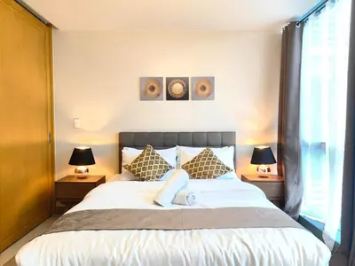 a bedroom with a large bed with two lamps at Uptown BGC Spacious 1BR Unit by Terravista - Prague Suite in Manila