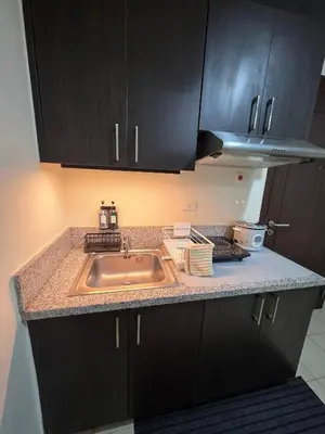 a kitchen counter with a sink and black cabinets at Pioneerwoodlands Mandaluyong Studio Unit in Manila