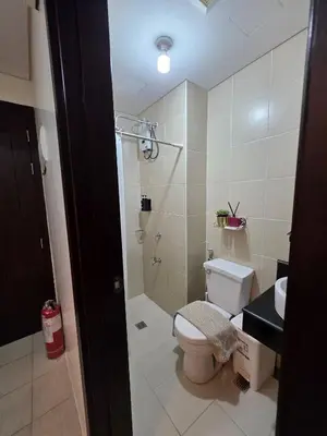 a bathroom with a toilet and a shower and a sink at Pioneerwoodlands Mandaluyong Studio Unit in Manila