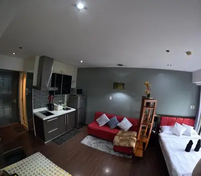 a living room with a red couch and a kitchen at 56th Floor -Sauna - Makati View - Knightsbridge Residences in Manila