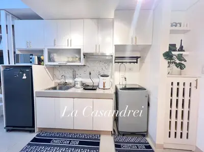 a kitchen with white cabinets and a black refrigerator at La Casandrei in Dasmariñas