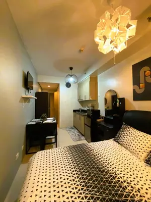 a bedroom with a large bed and a kitchen at Chateau Staycation in Manila