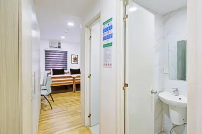 a hallway with a bathroom with a sink and a desk at Belvilla College Residences In University Belt, Metro Manila in Manila