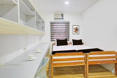 a small room with a bed and a table and chairs at Belvilla College Residences In University Belt, Metro Manila in Manila