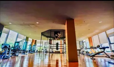 a gym with cardio equipment in a large room with windows at LeMoon's Chill with beautiful view-1 Bedroom in Manila