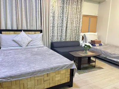 a bedroom with a bed and a couch and a table at Walking Distance Condo Across Naia T3 Airport in Manila