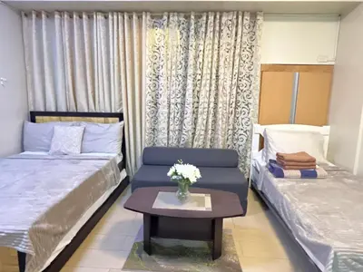a bedroom with two beds and a table with a vase of flowers at Walking Distance Condo Across Naia T3 Airport in Manila