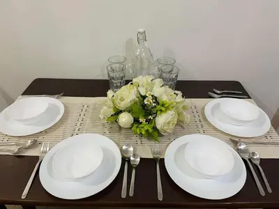 a table with white plates and a bouquet of flowers at Kyedenz Unit -Two Palm Tree Villas Newport Naia T3 in Manila