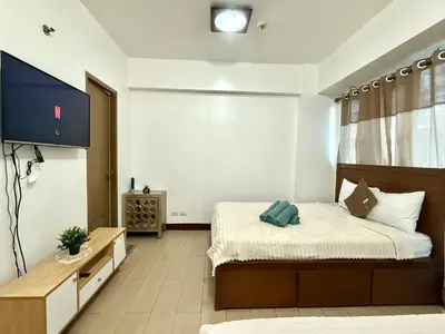 a bedroom with a bed and a flat screen tv at Kyedenz Unit -Two Palm Tree Villas Newport Naia T3 in Manila