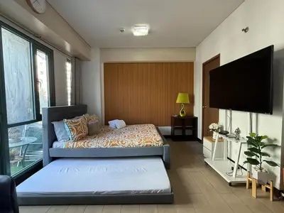 a bedroom with a bed and a flat screen tv at Lovely Condo Across NAIA T3 Newport with WiFi in Manila