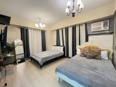 a bedroom with two beds and a chandelier at Kyendenz Condotel-Across Naia T3 Pool View with Wifi in Manila