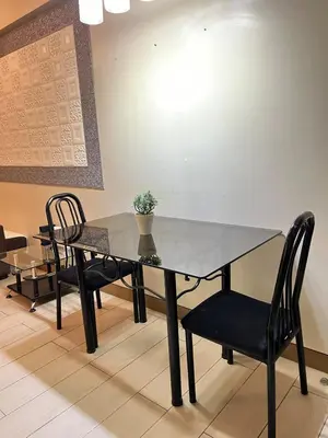 a dining room table with two chairs and a glass table at Kyendenz Condotel-Across Naia T3 Pool View with Wifi in Manila