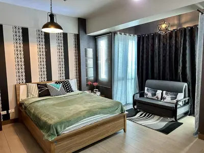 a bedroom with a bed and a chair in it at Homey Studio at Two Palm Tree Across NAIA T3 Airport in Manila