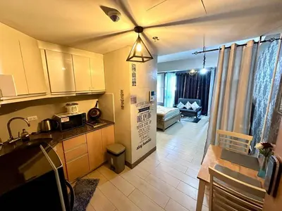 a kitchen with a ceiling fan and a living room at Homey Studio at Two Palm Tree Across NAIA T3 Airport in Manila