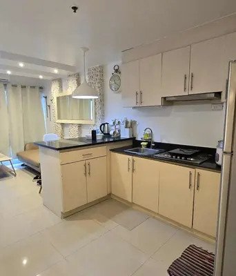 a kitchen with white cabinets and a stove top oven at Staycation in Paranaque by Indigo in Manila