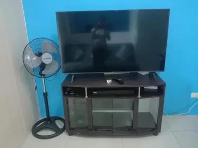 a television on a tv stand with a fan at Luxurious Condo in the Heart of Makati Philippines in Manila