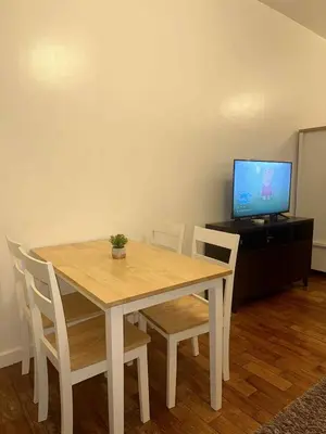 a wooden table with chairs and a television on a cabinet at Spacious Studio in Mosaic Tower no Balcony in Manila