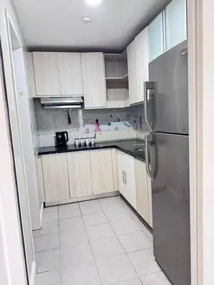 a kitchen with wooden cabinets and a stainless steel refrigerator at Near Moa Facing pool view WP1603 Monarch Parksuites in Manila