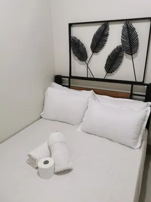 a white bed with two pillows and a roll of toilet paper at Mall of Asia condotel shore 3 residence in Manila