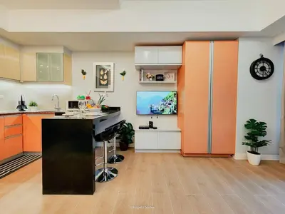 a kitchen with orange and white cabinets and a tv at One Bedroom Unit with Venice Canal View in Manila