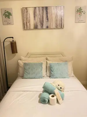a bed with a teddy bear sitting on it at Azure Staycations by MM 1 in Manila