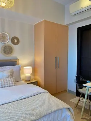a bedroom with a bed and a cabinet and a table at Cozy & Stylist Unit in BGC in Manila