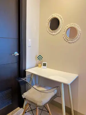 a table with a chair and two mirrors on the wall at Cozy & Stylist Unit in BGC in Manila