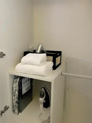 a shelf with towels and a phone on it in a bathroom at Cozy Netflix and Chill in BGC in Manila