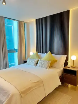 a bedroom with a large white bed with a window at Netflix and Chill Cozy Unit BGC in Manila