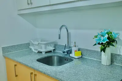 a kitchen counter with a sink and a vase of flowers at Chill Luxe Vista in Manila