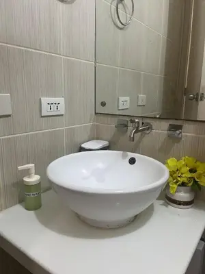 a bathroom with a white sink and a mirror at JFS Home at Birch Tower in Manila