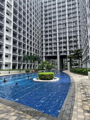 a swimming pool in front of a tall building at Cozy Condo Staycation with Balcony near Mall of Asia in Manila