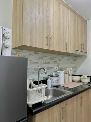 a kitchen counter with a sink and a refrigerator at Cozy Condo Staycation with Balcony near Mall of Asia in Manila