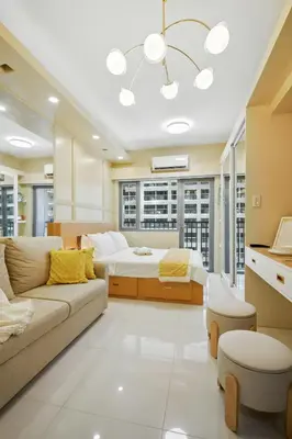 a living room with a bed and a couch at The Sunny Flat at Fame Residences near SM Megamall, Shangrila in Manila