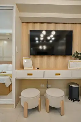 a bedroom with a tv on a wall with two stools at The Sunny Flat at Fame Residences near SM Megamall, Shangrila in Manila
