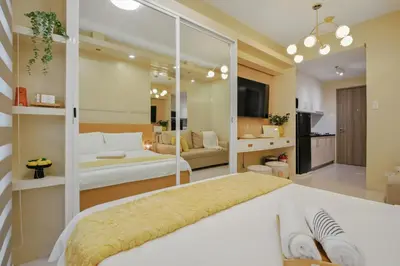 a bedroom with two beds and a living room at The Sunny Flat at Fame Residences near SM Megamall, Shangrila in Manila