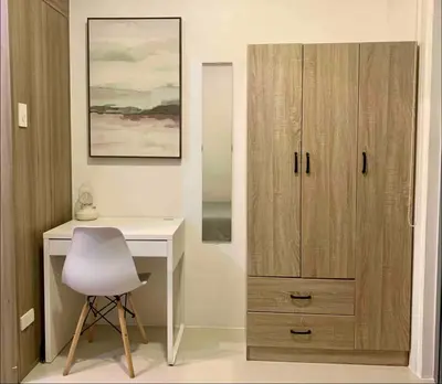 a desk with a white chair next to a wooden cabinet at Fame Residences One-Bedroom Condo Unit in Manila