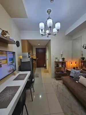 a living room with a couch and a chandelier at MOA Shell Residences Spacious 1BR with City View WiFi and Netflix in Manila
