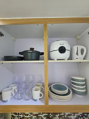 a cabinet with plates and cups and a toaster at MOA Shell Residences Spacious 1BR with City View WiFi and Netflix in Manila