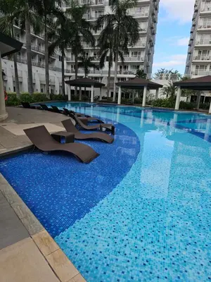 a large swimming pool with chairs in a building at MOA Shell Residences Spacious 1BR with City View WiFi and Netflix in Manila