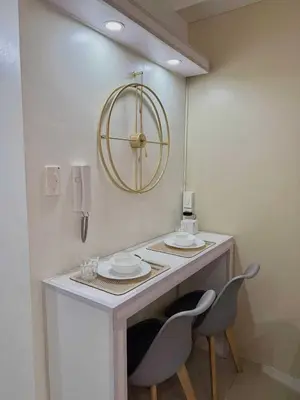 a table with two chairs and a clock on the wall at Aurbana Staycation in Manila