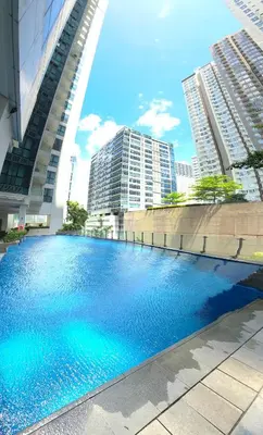 a large swimming pool in a city with tall buildings at Explore Mitsukoshi Uptown BGC, large TV, fast WIFI in Manila