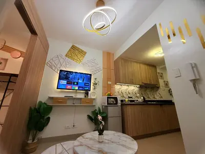 a kitchen with a table and a tv on the wall at Shore 2 Residences Tower 3 by HappyHaven in Manila