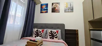 a bedroom with a bed with pillows and pictures on the wall at JJMC PLACE 28 With Netflix and Unli Wifi in Manila