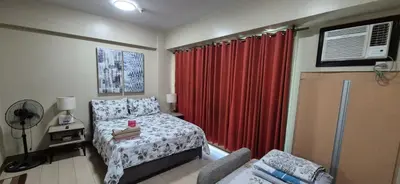 a bedroom with a bed and a red curtain at Rqui Condotel Newport Pasay City in Manila