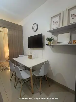 a dining room table with chairs and a clock on a wall at Cozy 19 at Shore 2 Residences in Manila