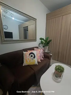 a living room with a couch and a mirror at Cozy 19 at Shore 2 Residences in Manila
