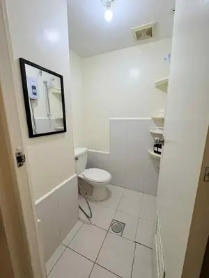 a white bathroom with a toilet and a mirror at JJMC HOMESTAY 29 with Netflix and Wifi in Manila