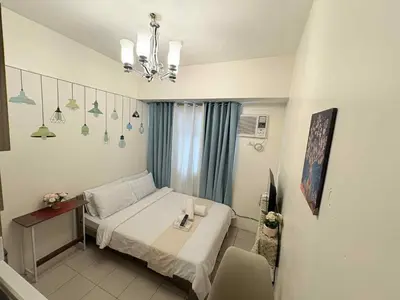 a bedroom with a bed and a table and a chandelier at JJMC PLACE 29 With Netflix and Unli Wifi in Manila
